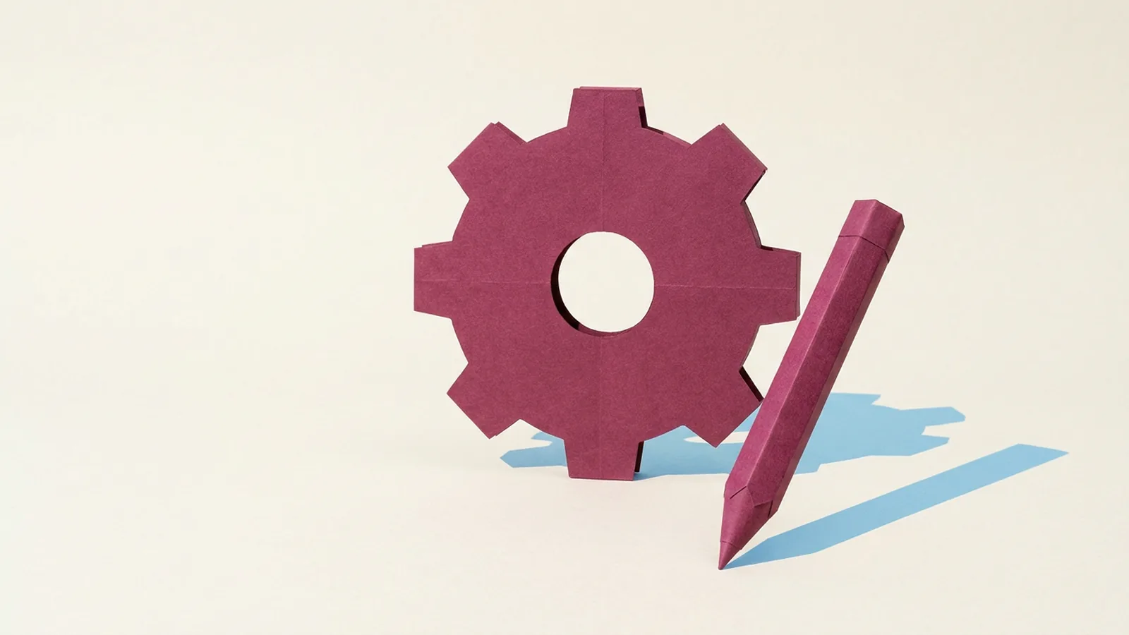Paper-craft illustration of a deep wine paper pencil leaning against a large paper gear