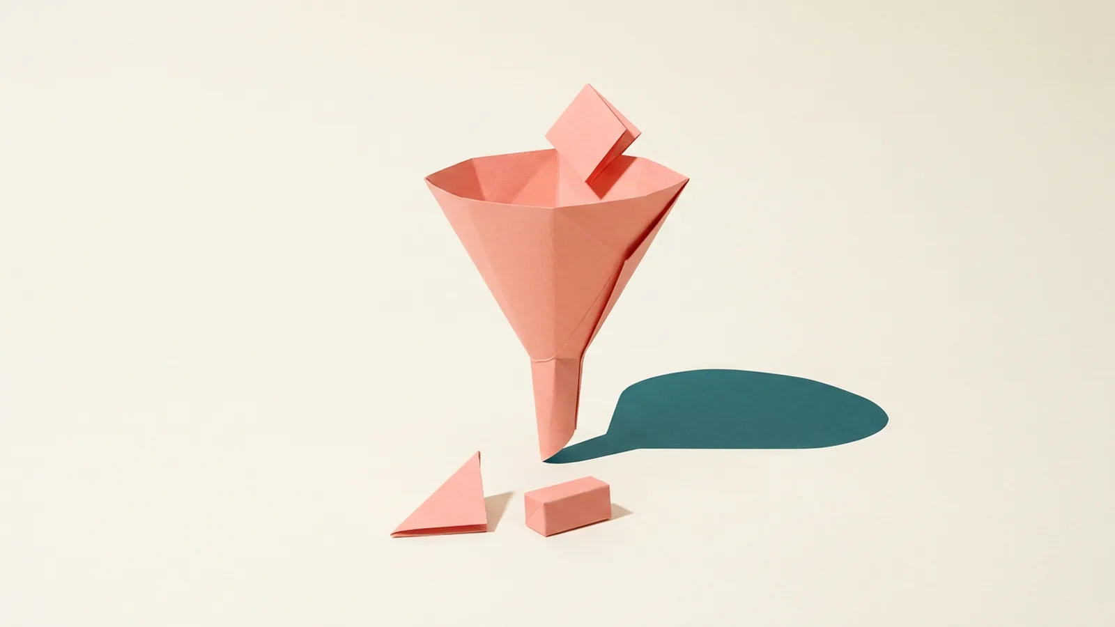 Paper-craft illustration of a single folded paper funnel with one folded piece dropping into its wide top opening and two differently shaped folded pieces resting below its narrow spout